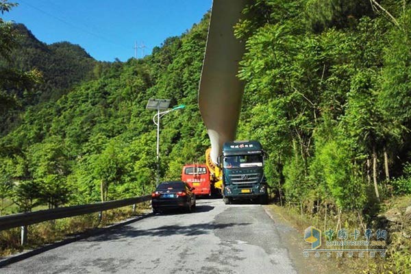 杰獅牽引車裝載風(fēng)車葉片在上山路上